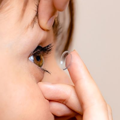 White woman putting in a contact lens.